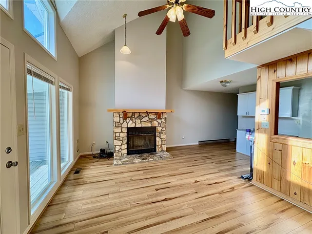 a view of an empty room with wooden floor and a fireplace