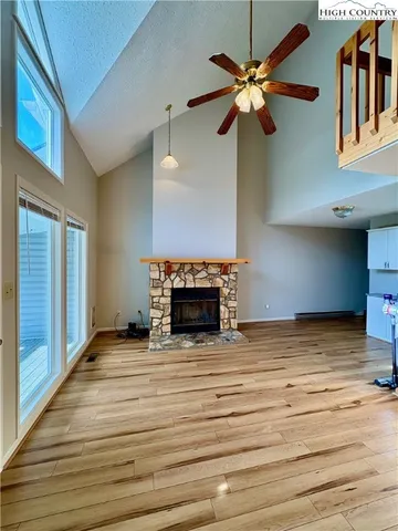 a view of an empty room with a ceiling fan and a fireplace
