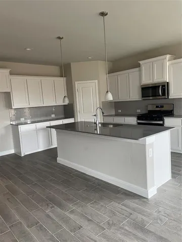 a kitchen with stainless steel appliances granite countertop a stove a sink and white cabinets