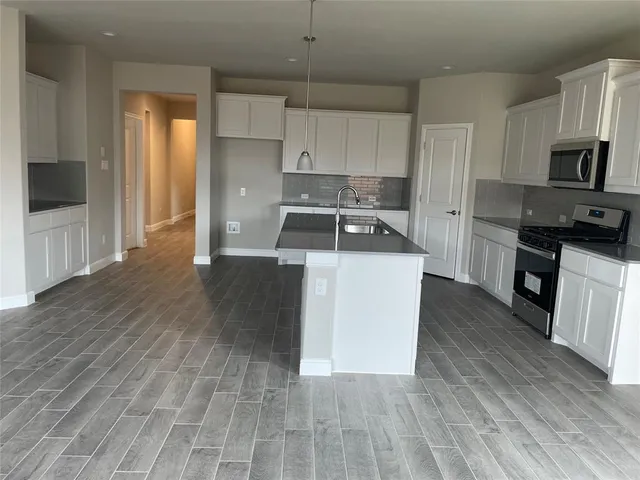 a kitchen with a sink a stove top oven and wooden floor