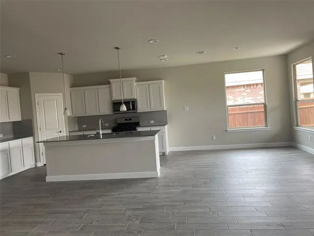 a kitchen with stainless steel appliances granite countertop a stove a sink and white cabinets