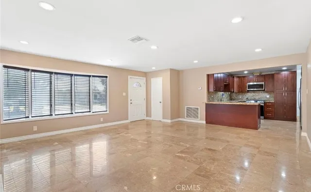 a large kitchen with kitchen island a large counter top stainless steel appliances and cabinets