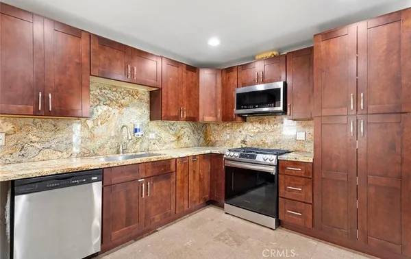 a kitchen with stainless steel appliances granite countertop wooden cabinets and a sink