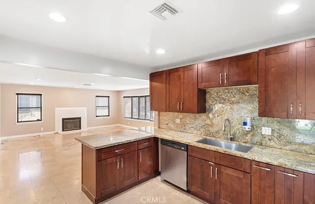 a kitchen with granite countertop a sink dishwasher stove and cabinets with wooden floor