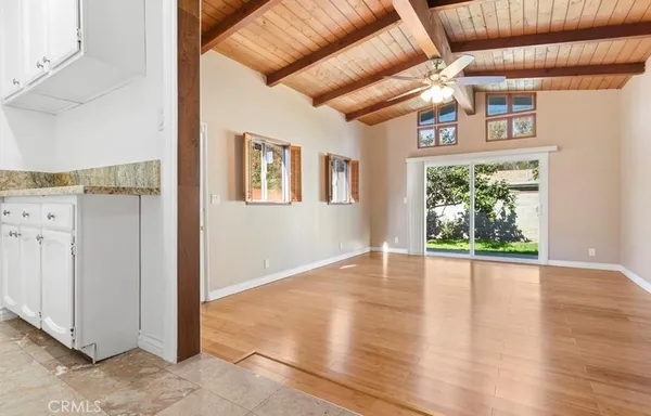 an empty room with wooden floor fan and windows