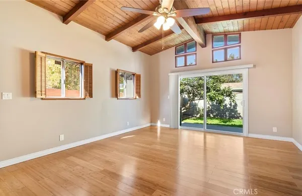 a view of an empty room with wooden floor and fan