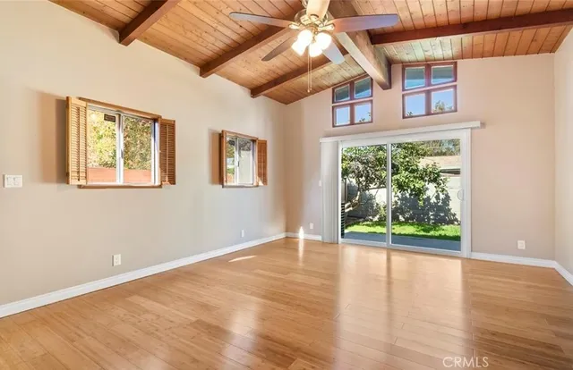 a view of an empty room with wooden floor and fan