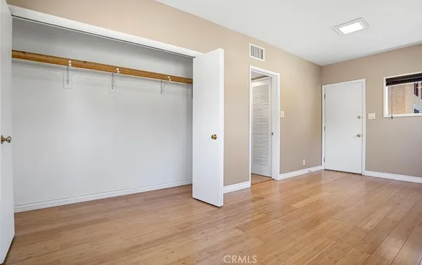 a view of an empty room with wooden floor and closet