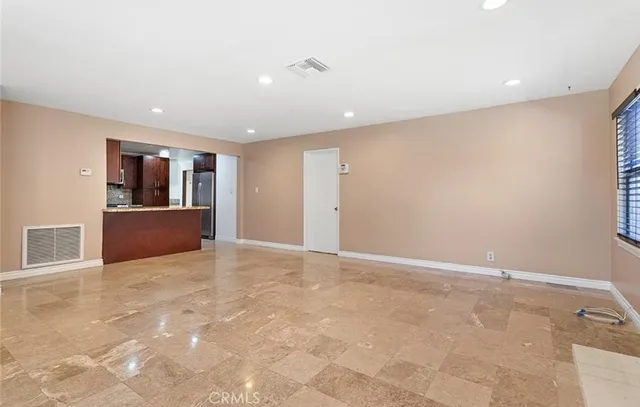 a view of an empty room with wooden floor and kitchen