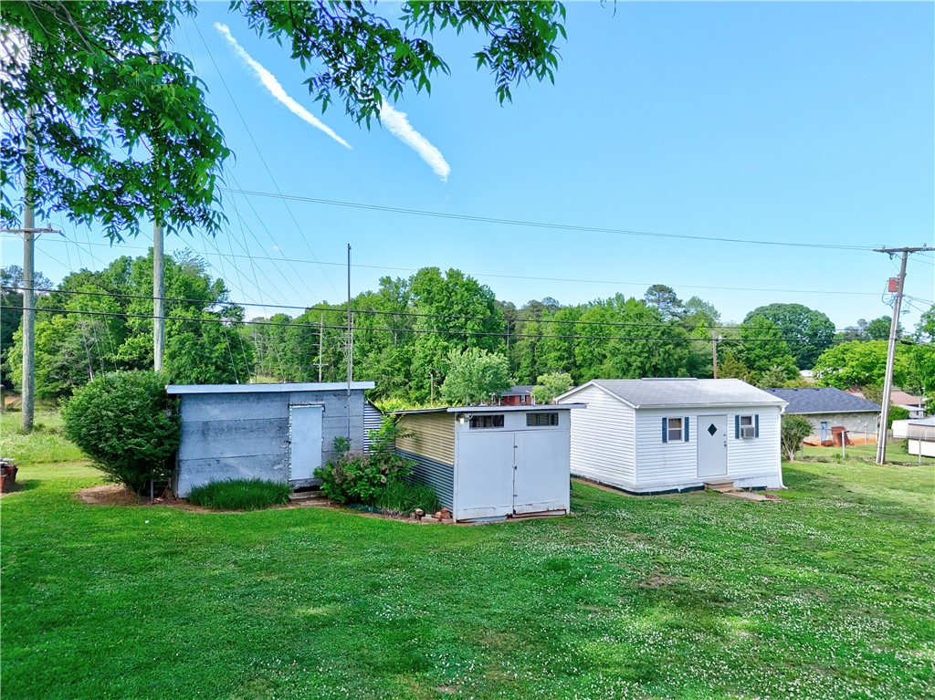307 Calhoun Road Belton, SC 29627 - Photo 10 of 30 A verdant lawn surrounds practical storage buildings, offering functional outdoor space.