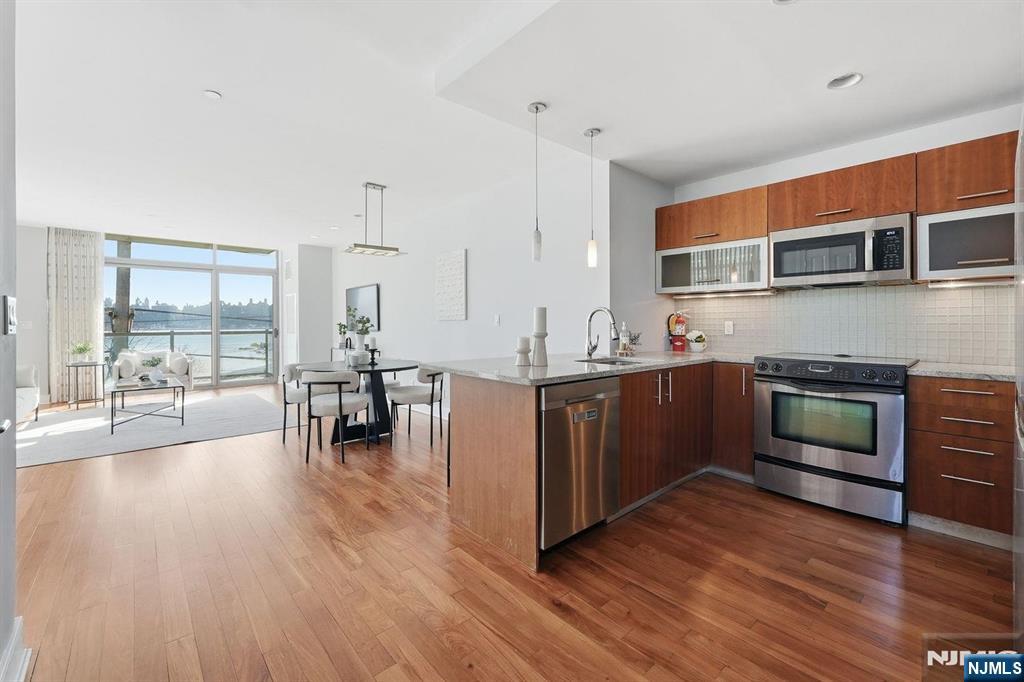 8125 River Road, Unit 4E North Bergen, NJ 07047 - Photo 9 of 35 a kitchen with stainless steel appliances kitchen island wooden floors and white cabinets