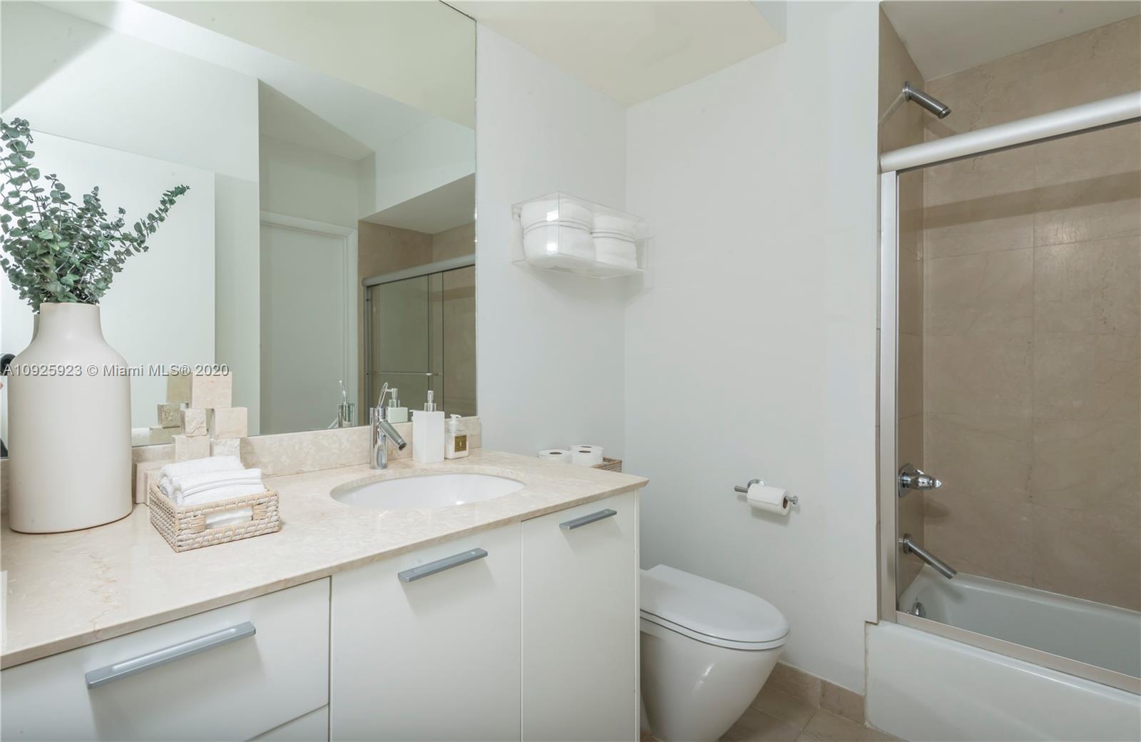 400 Alton Road, Unit 1007 Miami Beach, FL 33139 - Photo 11 of 13 a bathroom with a granite countertop sink a toilet and a mirror