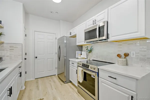 a kitchen with stainless steel appliances white cabinets and a stove top oven
