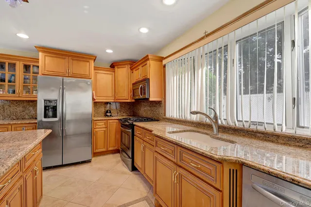 a kitchen with stainless steel appliances granite countertop a sink a stove and a refrigerator