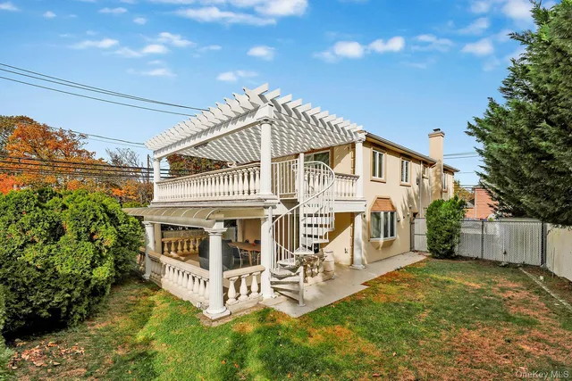 a view of a white house with large windows and a yard with plants