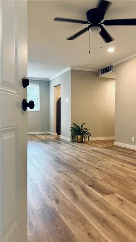 a view of a room with a ceiling fan and wooden floor