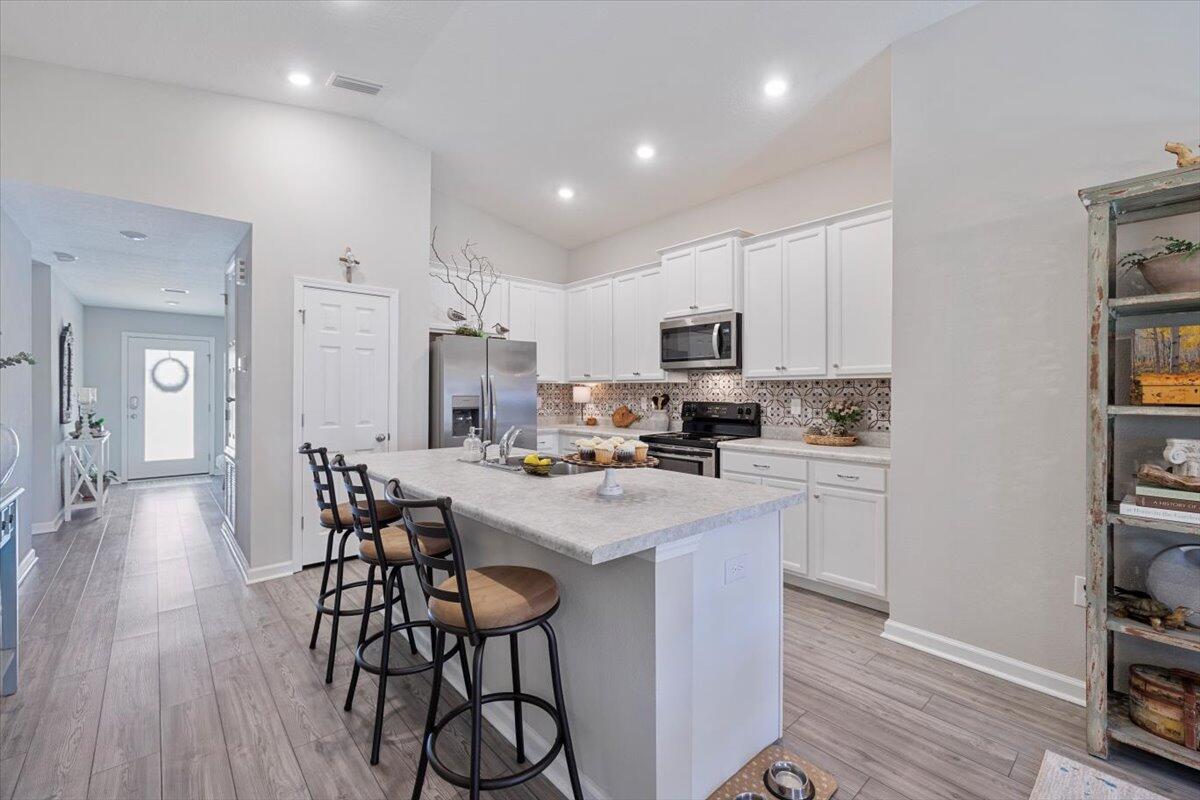 709 Riverwalk Circle Freeport, FL 32439 - Photo 8 of 28 a kitchen with stainless steel appliances a stove a refrigerator a sink dishwasher and a dining table with wooden floor