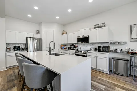 a kitchen with stainless steel appliances granite countertop a sink a stove a refrigerator cabinets and chairs