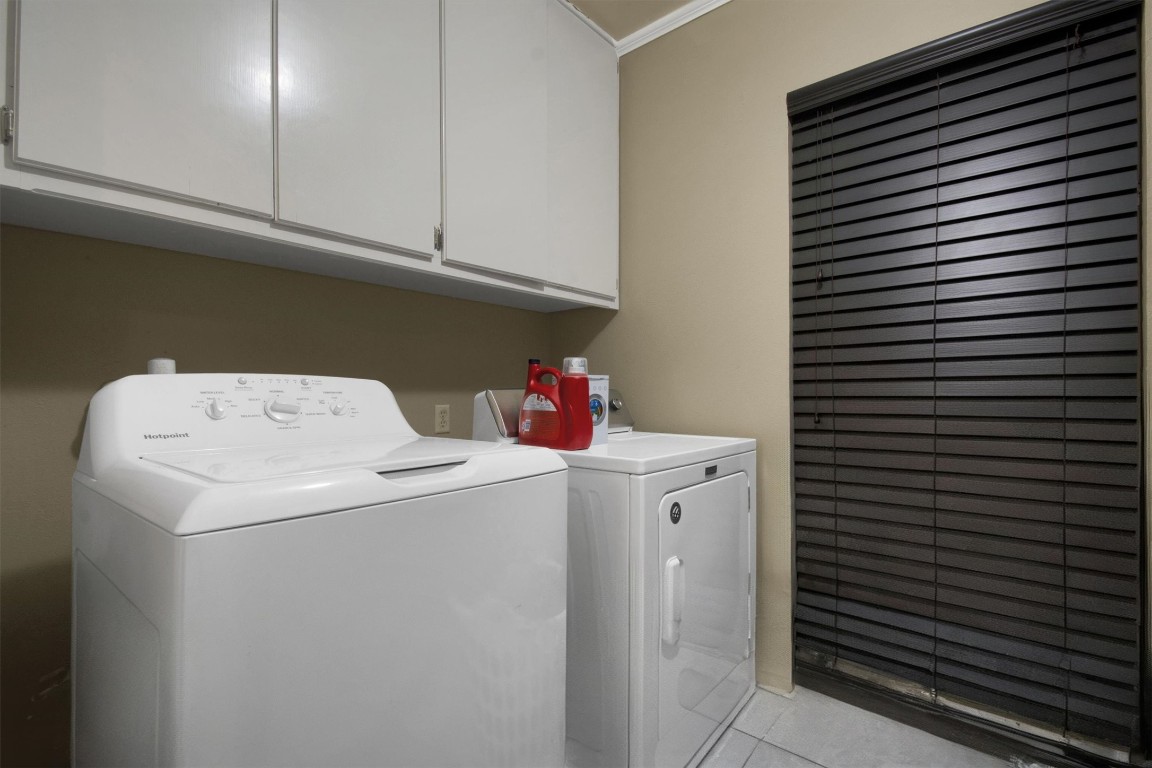416 Depot Street Elgin, TX 78621 - Photo 18 of 21 Laundry room featuring cabinet space, washer and clothes dryer, crown molding, and light tile patterned floors
