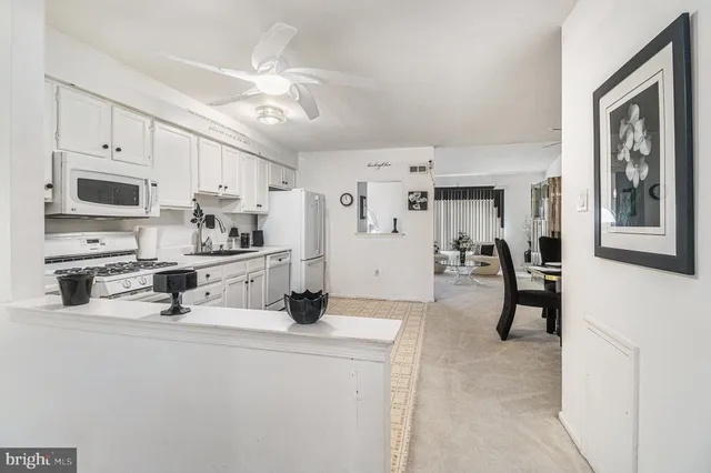 a kitchen with stainless steel appliances a refrigerator a stove top oven a sink dishwasher and white cabinets