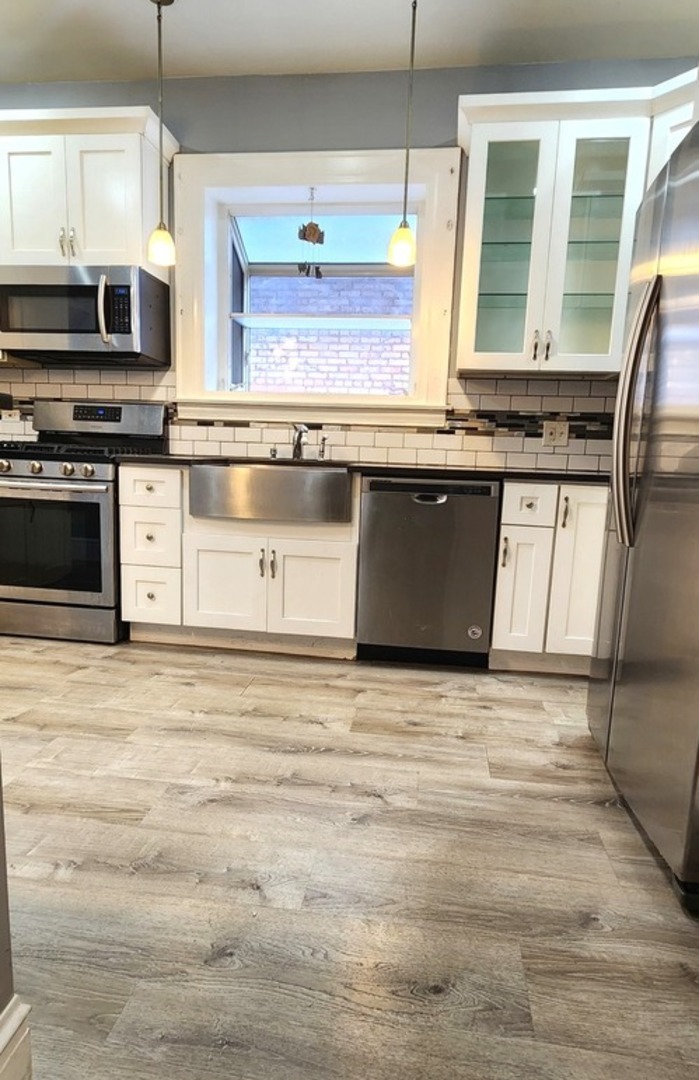 7227 South Bennett Avenue Chicago, IL 60649 - Photo 18 of 47 a kitchen with stainless steel appliances granite countertop a stove a sink and a microwave
