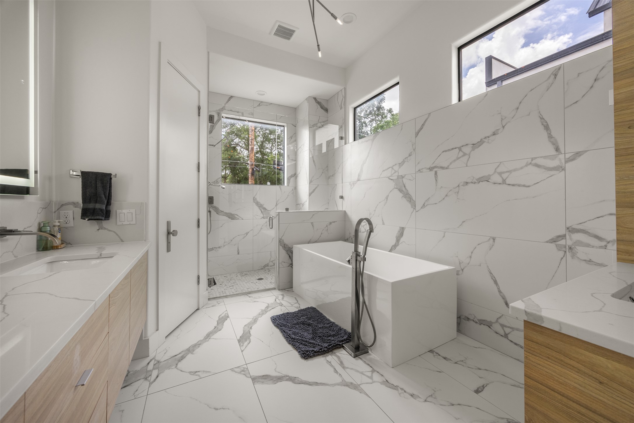 4103 Ridgelea Drive Austin, TX 78731 - Photo 16 of 26 Luxurious spa-like bathroom features a standalone tub and sleek marble-inspired tile throughout.