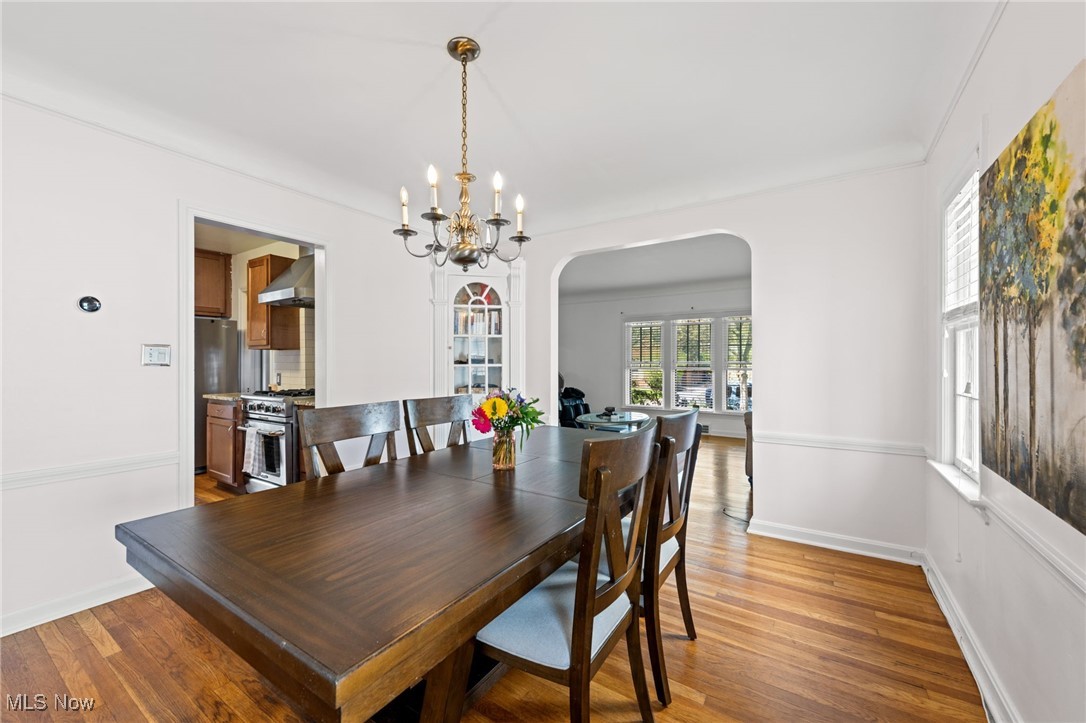 2471 Channing Road Cleveland, OH 44118 - Photo 12 of 33 Dining room featuring arched walkways, baseboards, light wood finished floors, and a chandelier