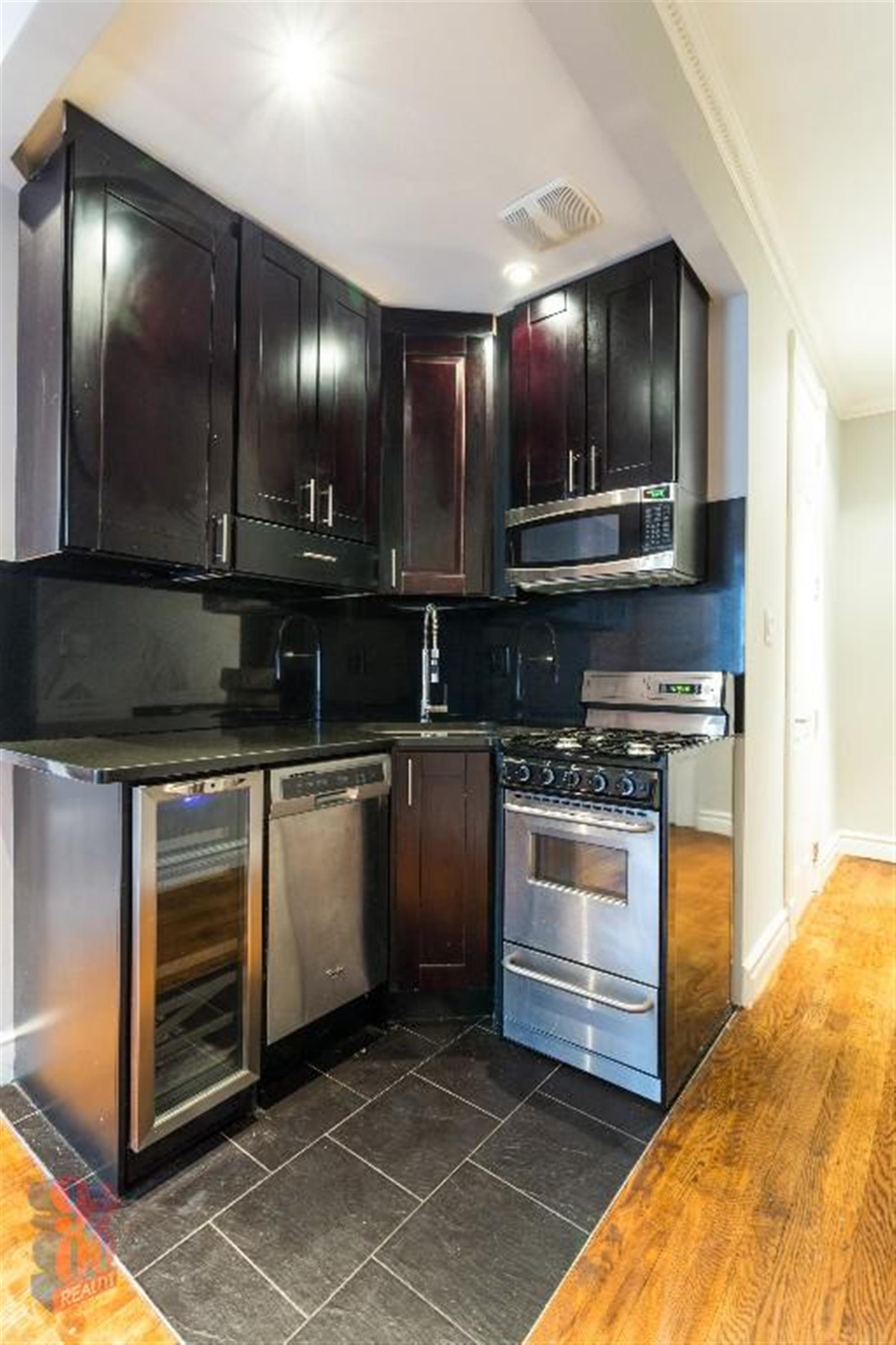 250 Mott Street, Unit 13 Manhattan, NY 10012 - Photo 4 of 5 a kitchen with stainless steel appliances kitchen island granite countertop a stove a sink and a microwave