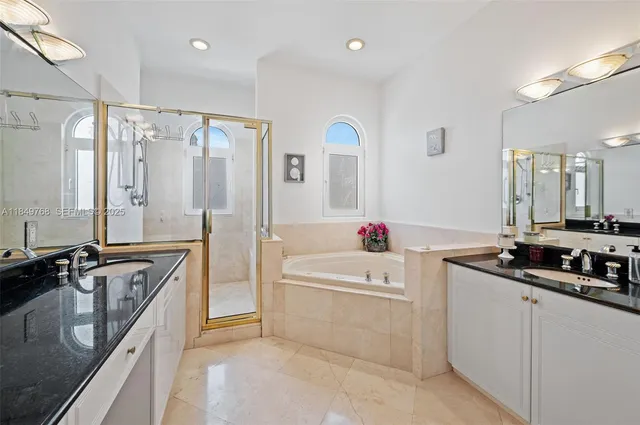 a bathroom with a granite countertop double vanity sink a mirror and a bathtub