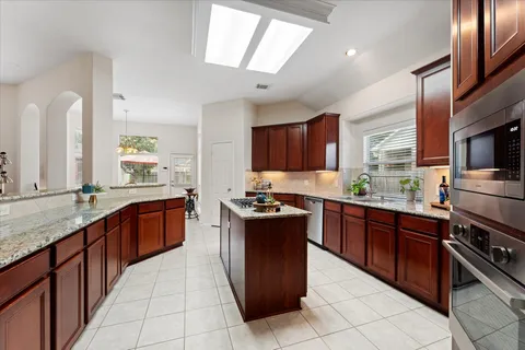 a kitchen with stainless steel appliances granite countertop wooden cabinets a stove top oven a sink and dishwasher