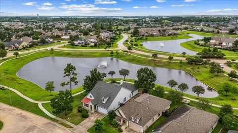 an aerial view of a house with a swimming pool a patio and lake view