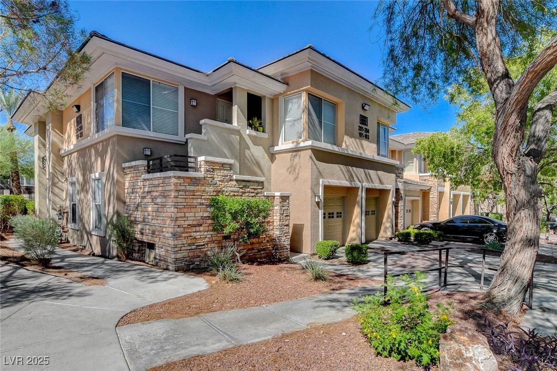Contemporary home featuring stucco siding, driveway, stone siding, and a garage