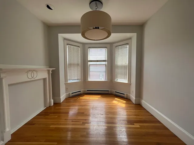 a view of an empty room with window and wooden floor