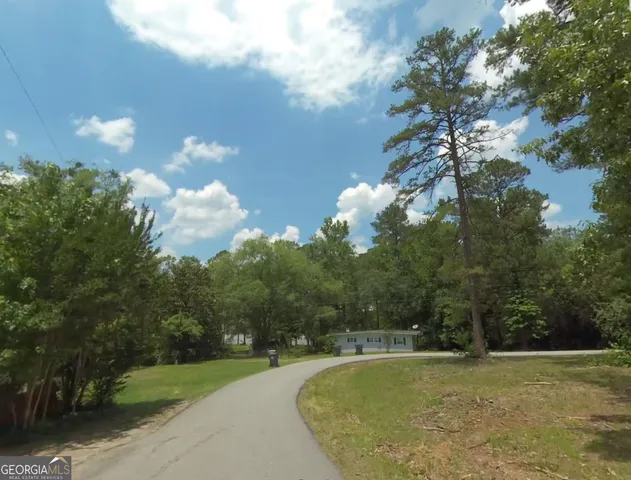 a view of a swimming pool with a yard and large trees