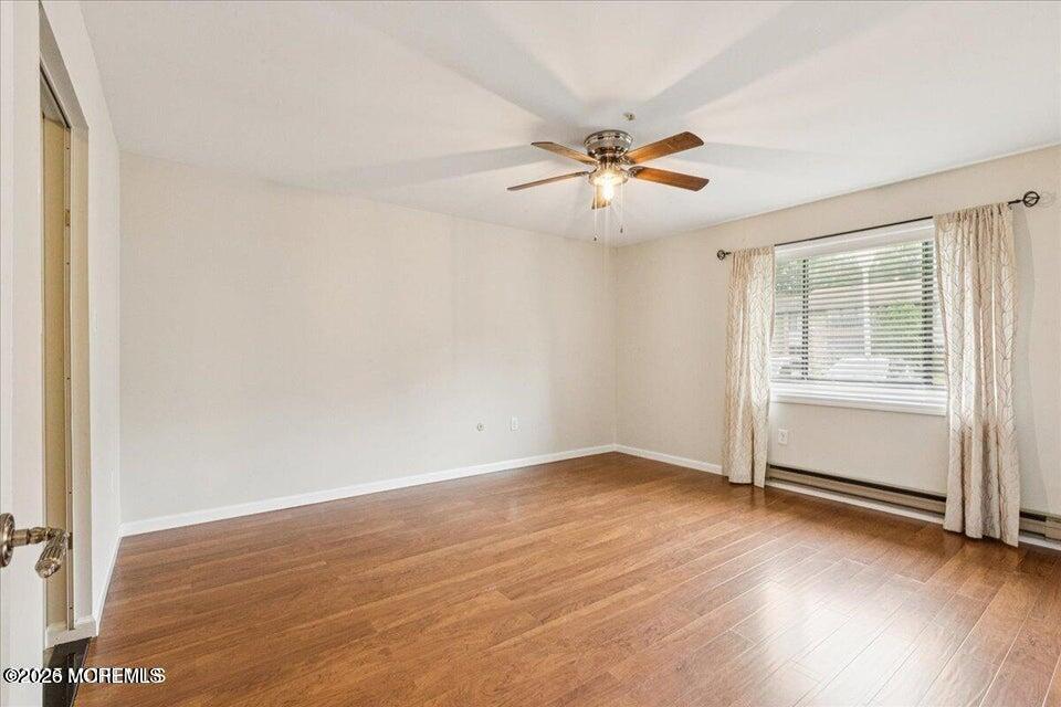 70 Overlook Way, Unit E Manalapan, NJ 07726 - Photo 11 of 20 an empty room with wooden floor fan and windows