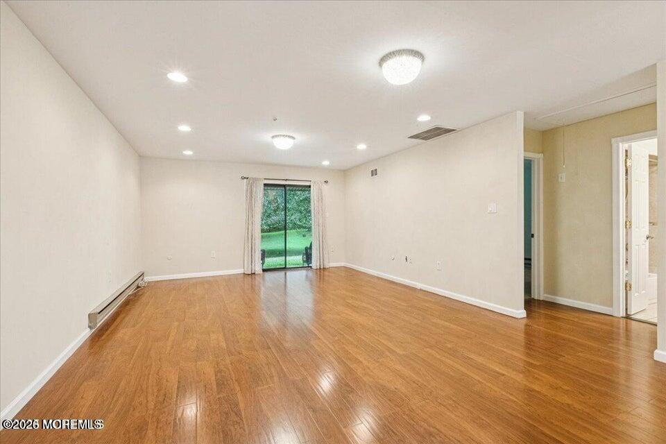 70 Overlook Way, Unit E Manalapan, NJ 07726 - Photo 9 of 20 a view of an empty room with wooden floor and a window