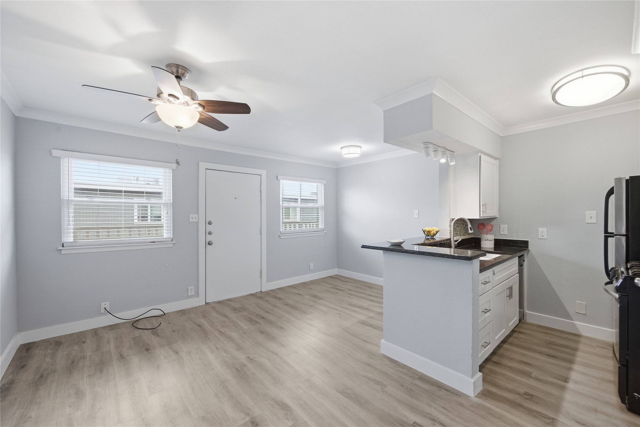 2401 Manor Road, Unit 232 Austin, TX 78722 - Photo 6 of 32 Kitchen featuring white cabinetry, a breakfast bar, ornamental molding, ceiling fan, and freestanding refrigerator