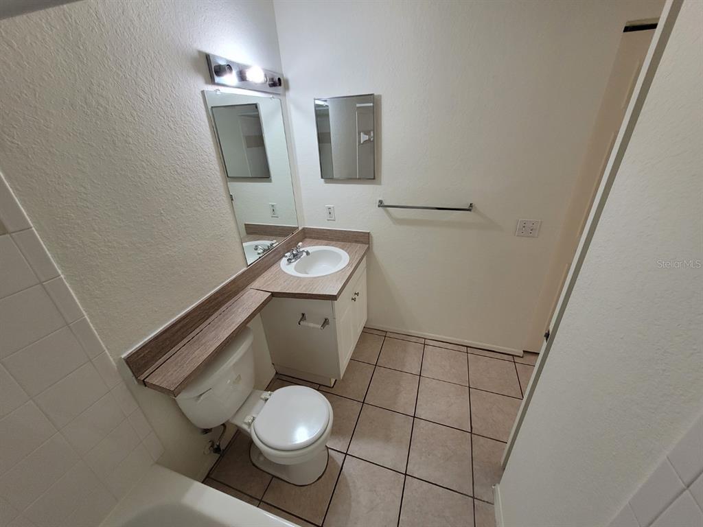 36037 Deer Creek Drive, Unit 102 Zephyrhills, FL 33541 - Photo 20 of 44 a white toilet sitting next to a bathroom sink and a mirror