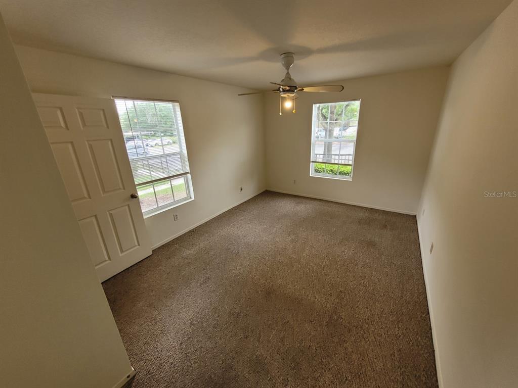 36037 Deer Creek Drive, Unit 102 Zephyrhills, FL 33541 - Photo 22 of 44 an empty room with windows and chandelier fan