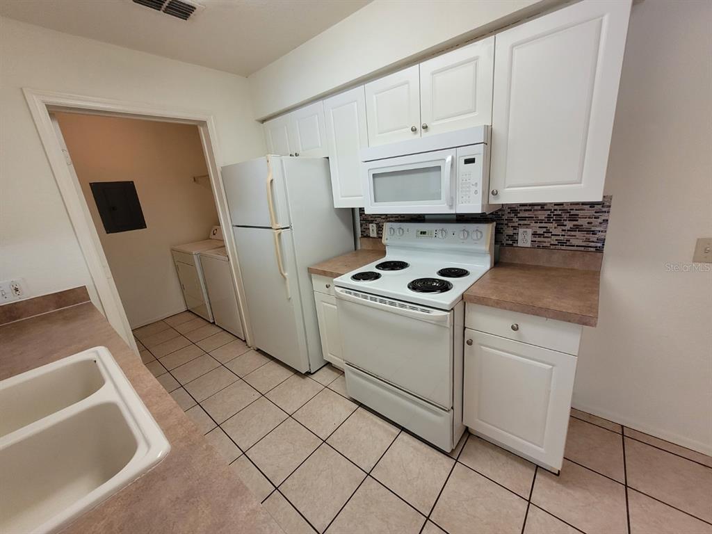 36037 Deer Creek Drive, Unit 102 Zephyrhills, FL 33541 - Photo 8 of 44 a kitchen with white cabinets and white appliances