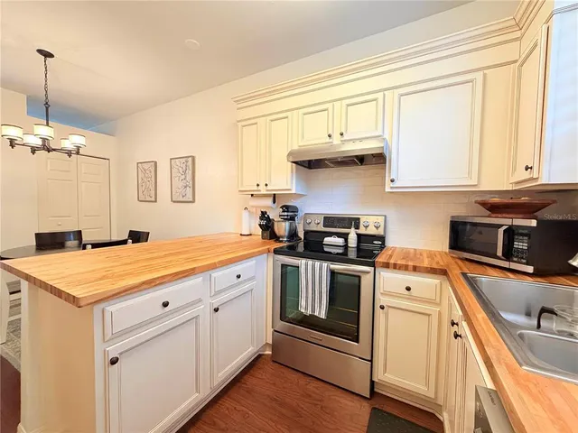 a kitchen with stainless steel appliances granite countertop a sink stove and white cabinets with wooden floor