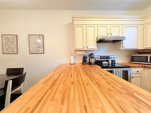 a kitchen with stainless steel appliances a stove a refrigerator a sink and white cabinets