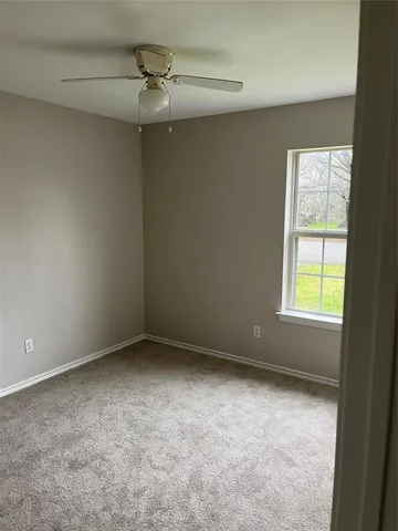 an empty room with a window and a fan