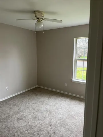 an empty room with a window and a fan