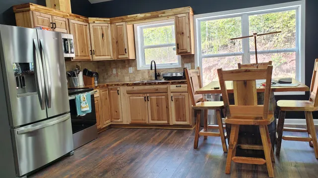 a kitchen with stainless steel appliances granite countertop a stove a refrigerator a sink a dining table and chairs with wooden floor