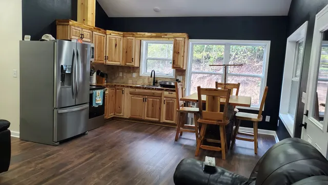 a kitchen with stainless steel appliances granite countertop a refrigerator a stove a sink dishwasher and a dining table with wooden floor