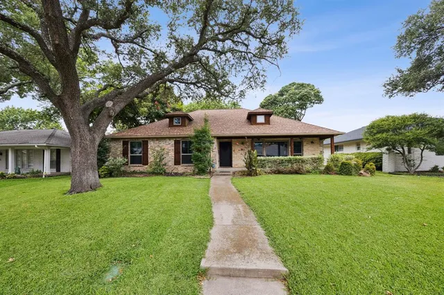 a front view of a house with a yard and trees