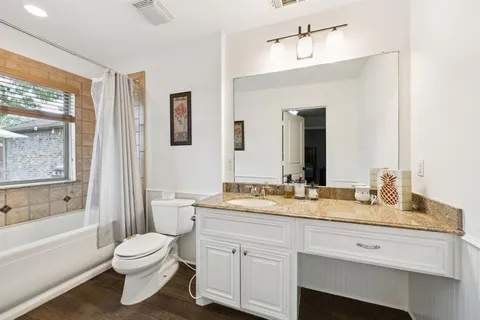 a bathroom with a granite countertop toilet sink and mirror
