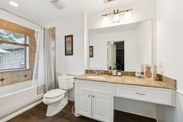 a bathroom with a granite countertop toilet sink and mirror