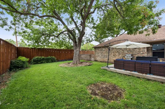 a view of a backyard with wooden fence and a large tree
